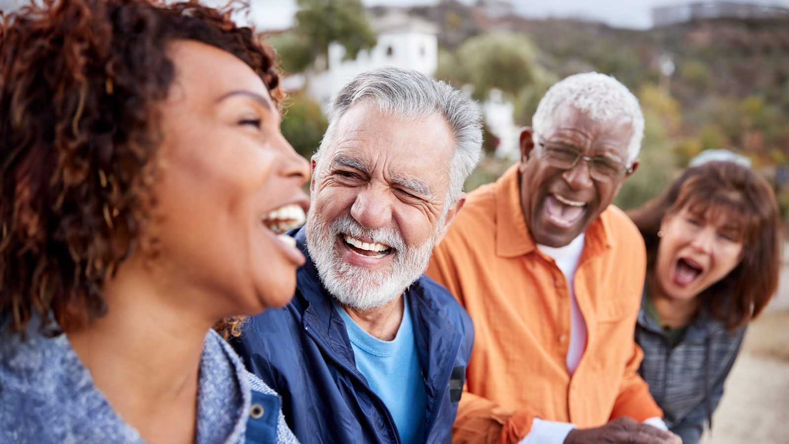 Four people are outdoors, laughing and enjoying themselves, embodying the vibrant spirit of the Silver Economy.