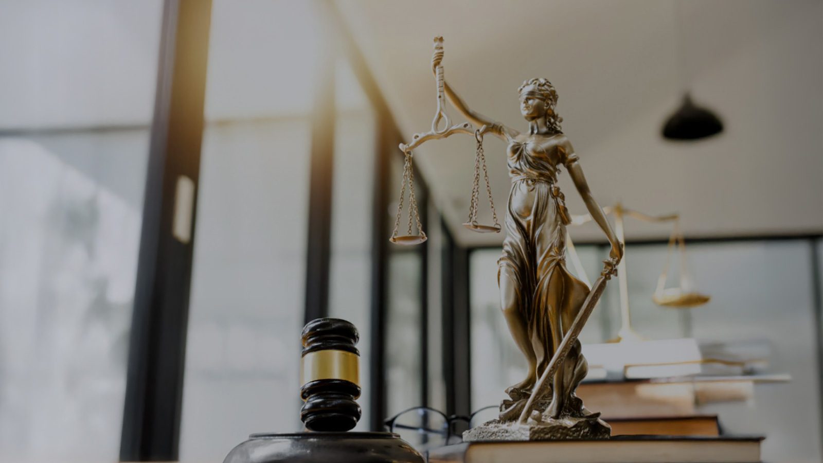 Lady Justice statue and gavel sit prominently on a desk in an office setting, symbolizing success in the legal industry.